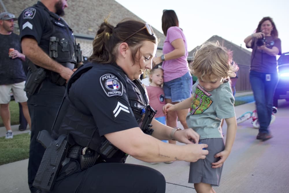 A Prosper police officer pins a light onto a young resident's shorts at an Oct. 1 National Night Out block party. (Alex Reece/Community Impact)
