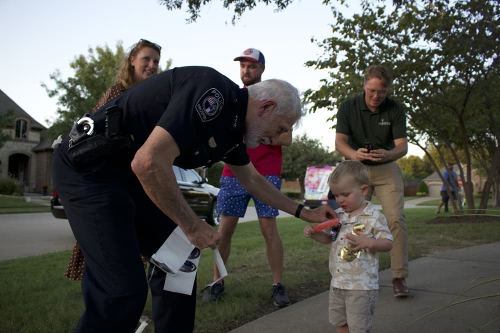 Prosper Police Chief Kowalski puts a sticker on a Prosper resident's shirt. (Alex Reece/Community Impact)