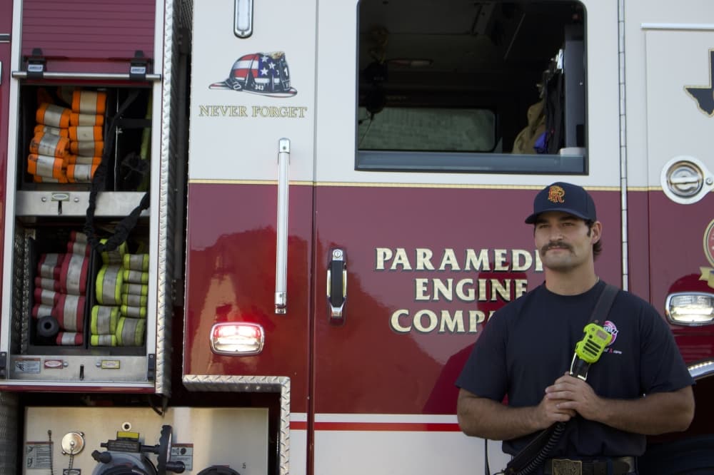 A Prosper firefighter stands next to a fire engine. (Alex Reece/Community Impact)