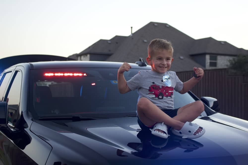 A young Prosper resident sits on a Prosper police car. (Alex Reece/Community Impact)