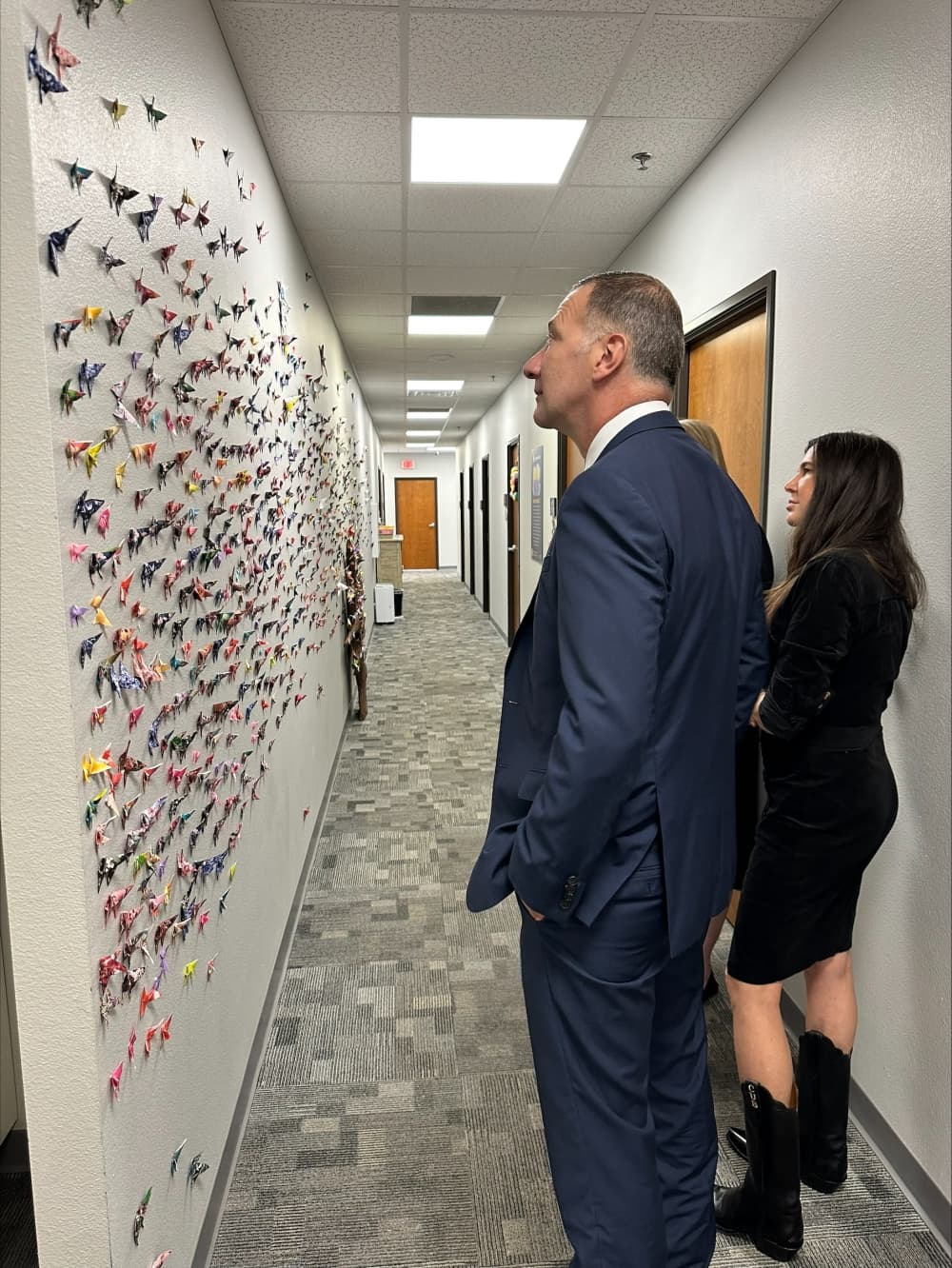 The senator looks at the wall of paper butterflies.