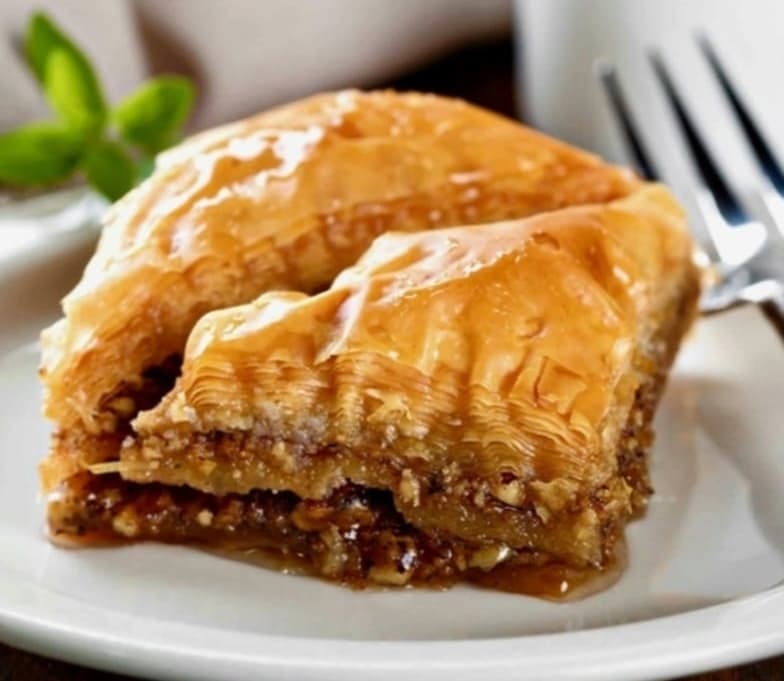 A slice of baklava is shown on a white plate.