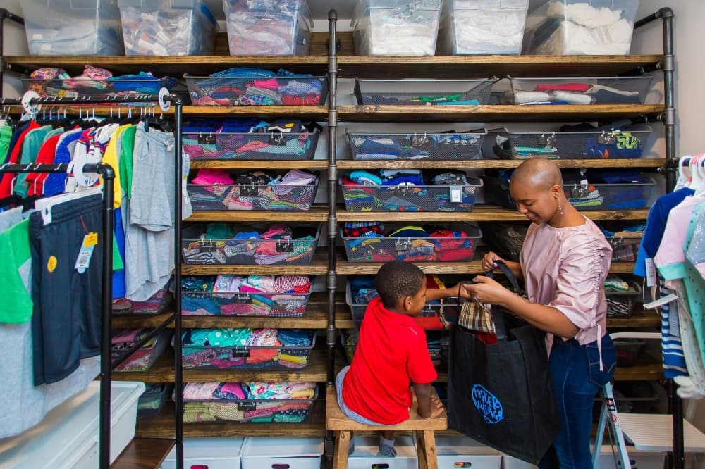 An image of a caregiver and a child picking out clothes from the resource center. 