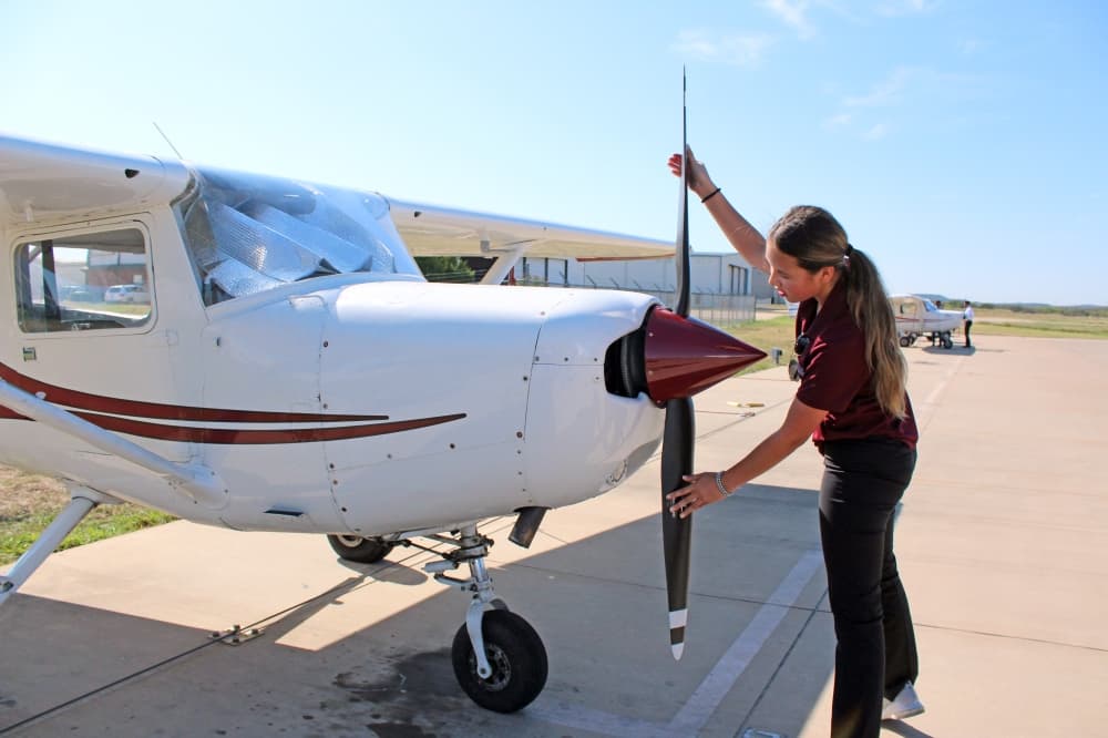 Female inspecting propeller of small plane. 