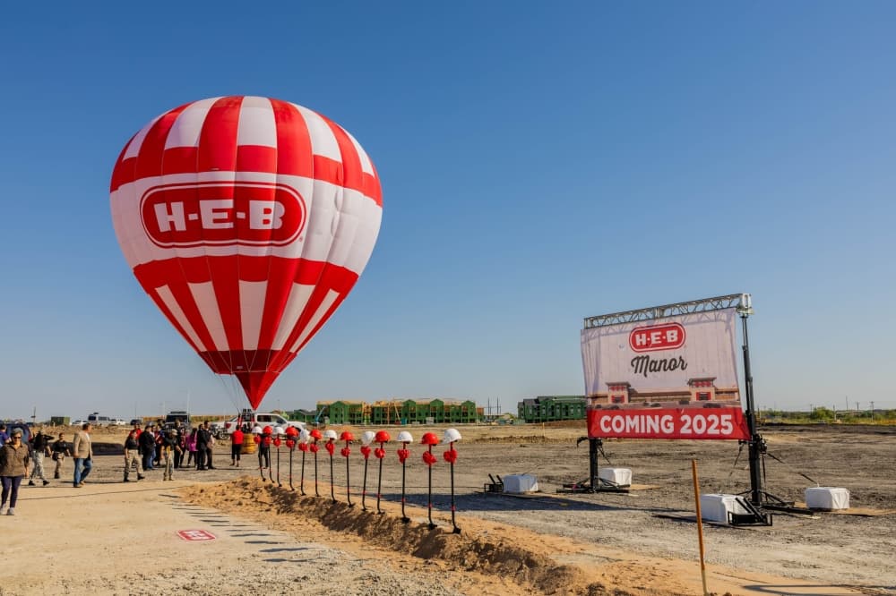 A red and white hot air balloon is shown next to the "coming soon" sign in Manor.