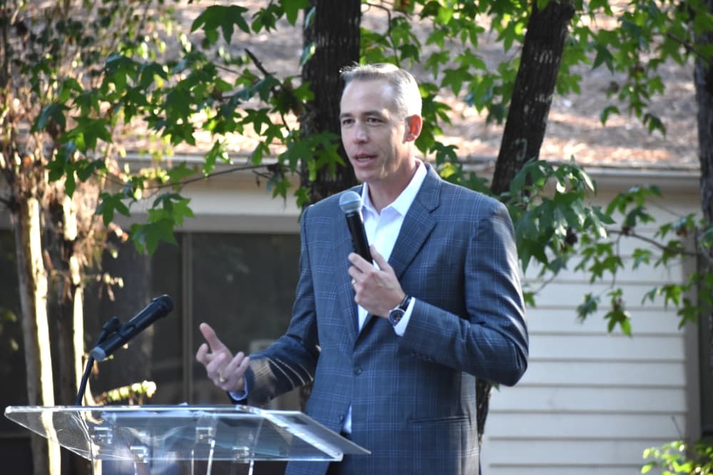man speaking at a podium outside