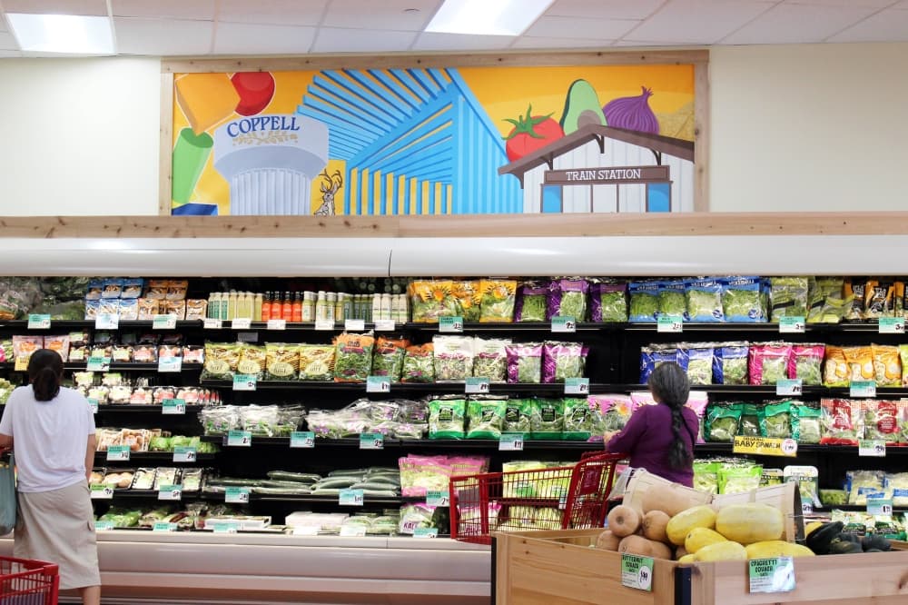 Grocery store with artwork over refrigerator section. 