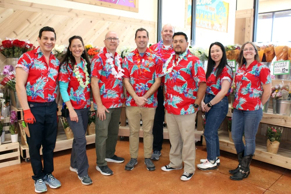 Group of males and females wearing Hawaiian shirts. 
