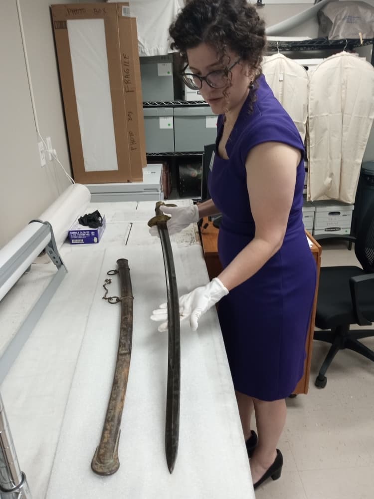 A woman inspects a sword.
