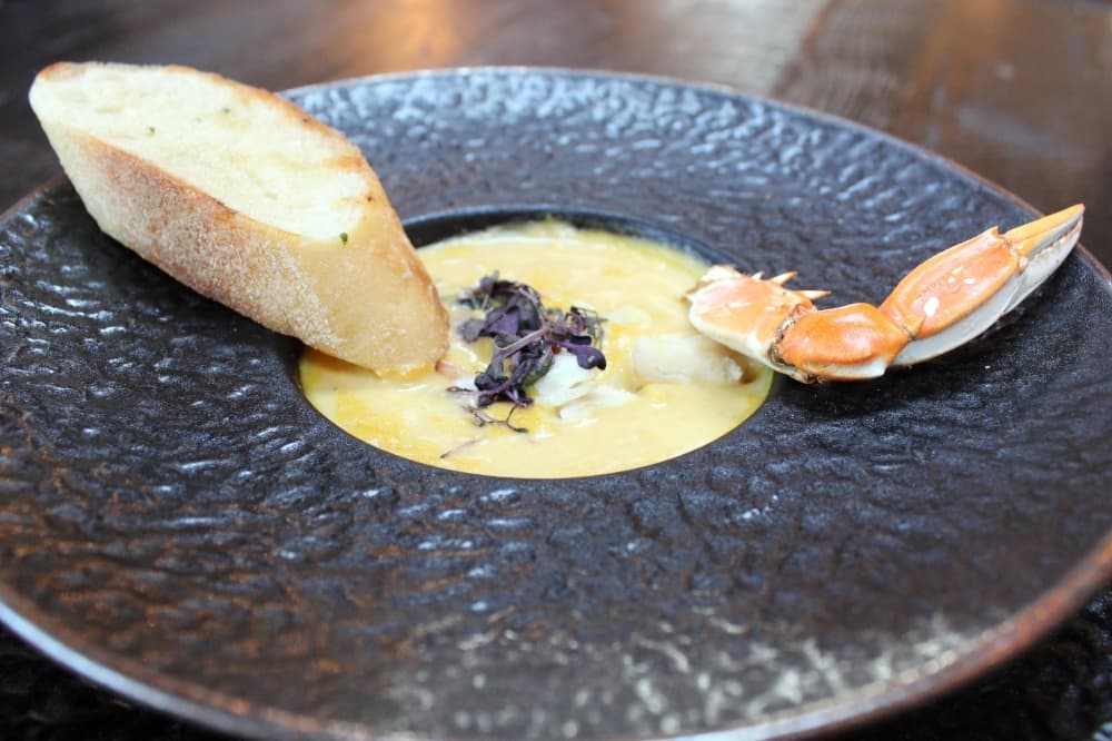 Bowl of crab bisque with bread on the side. 