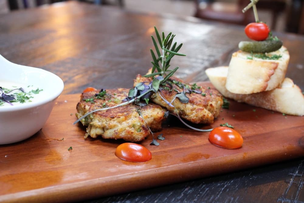 Crab cakes on a wooden serving board. 