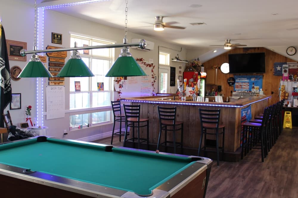 A pool table sits in front of a bar