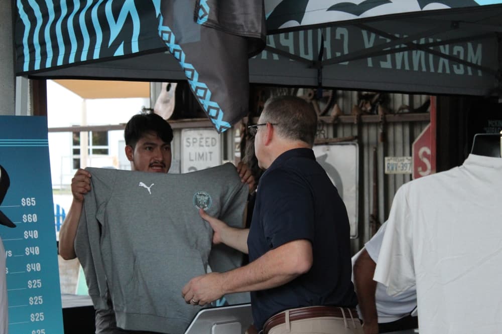 A McKinney Chupacabras FC representative shows a sweater featuring the team logo to a customer on Oct. 23 at Tupps Brewery.