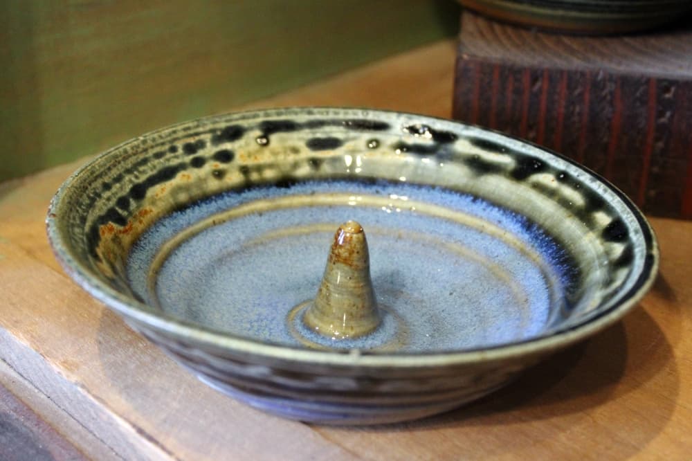 Circular piece of pottery with pointed cone in the middle. 