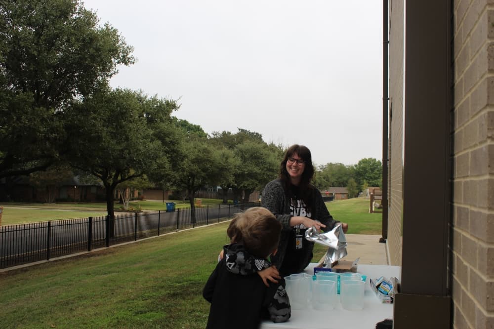First grade Teacher Cailin Beck pulls tin foil from a roll for students to use during a river flow activity.