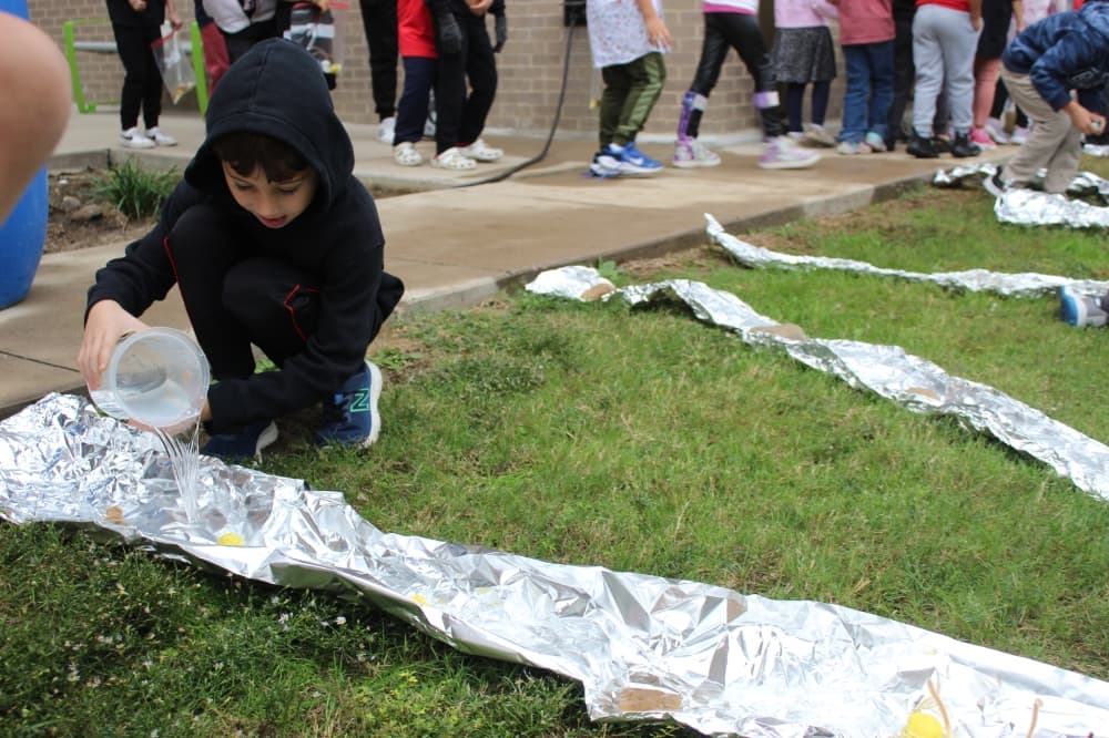 A first grade student pours water onto a line of tinfoil meant to simulate a river at Cannon Elementary School on Nov. 1.