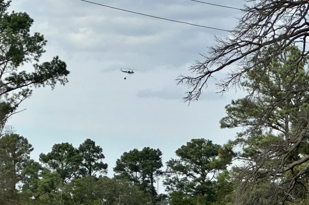A helicopter takes water to the fire.