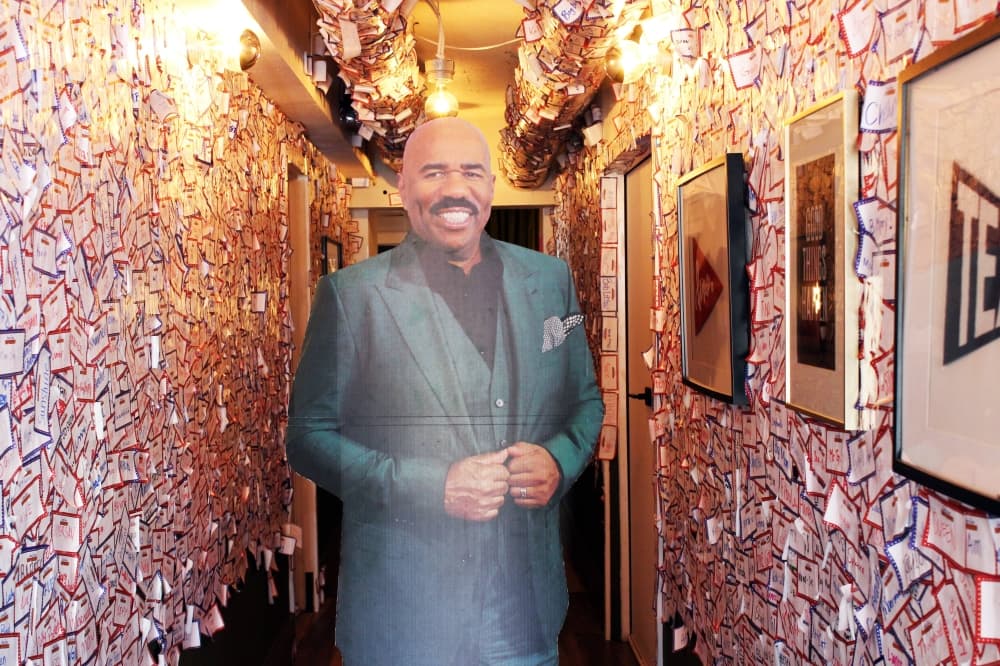Life size cutout of a male standing in a hallway with nametags stuck to the walls. 