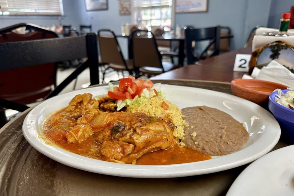 The pollo encebollado ($9.99) is chicken and sauteed onions topped with a red chile sauce. It comes with a side of rice, beans, and salad. (Thalia Guzman/Community Impact)