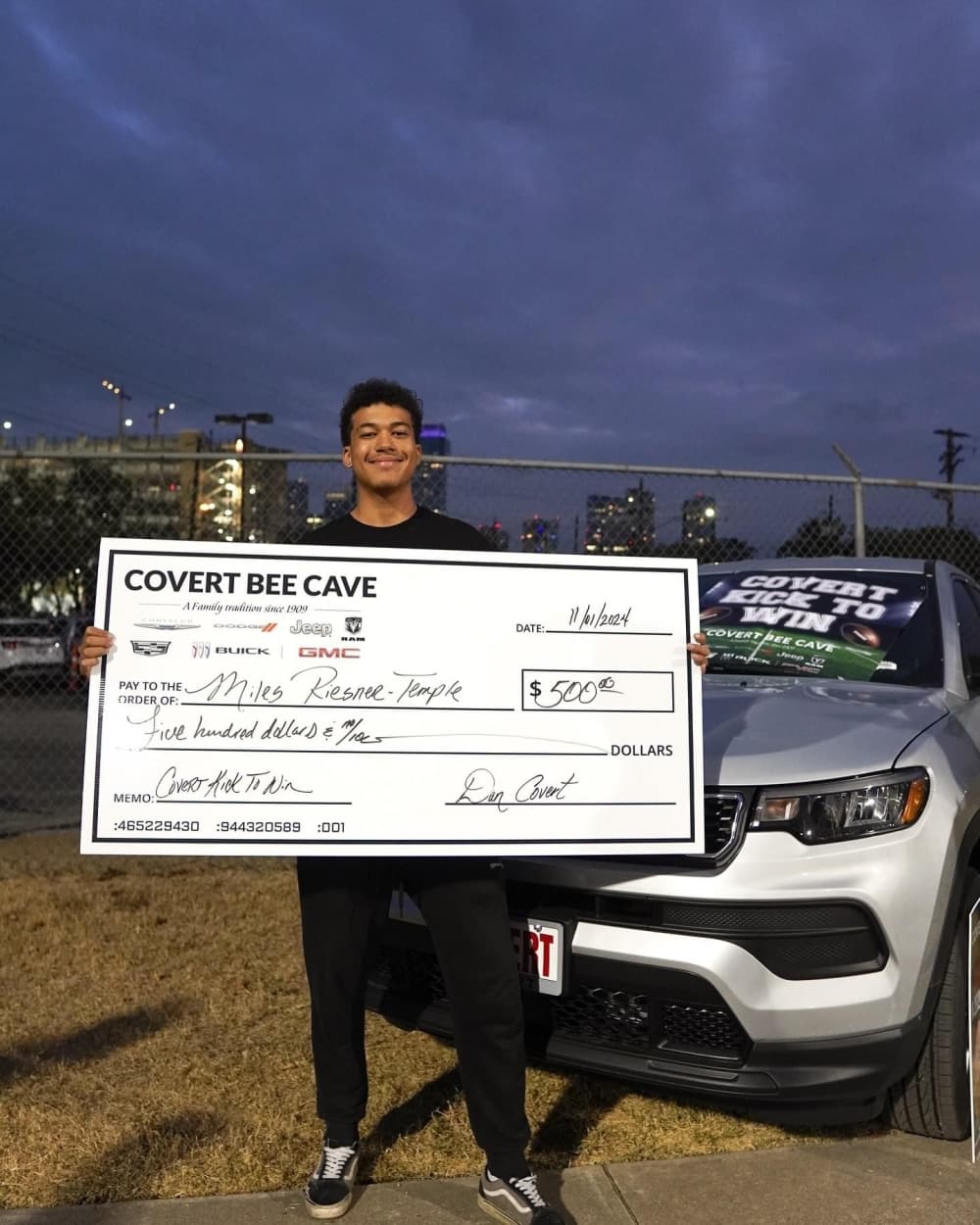 kid standing with $500 check