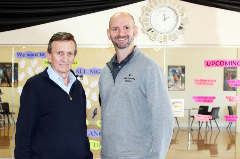 Two males standing in a dance studio. 