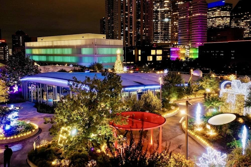 a park area with sidewalks is lit up with holiday lights 