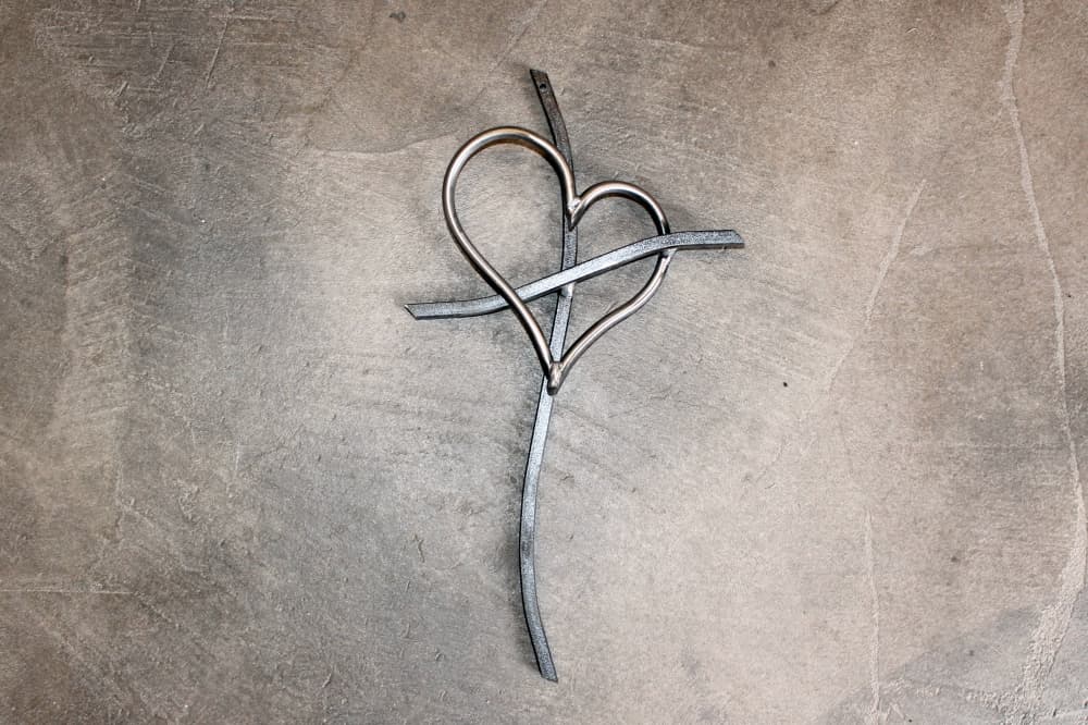 Metal cross with heart overlaying cross bars.