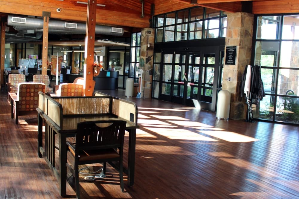 Interior of aroom with wooden architectural elements and floor to ceiling windows. 