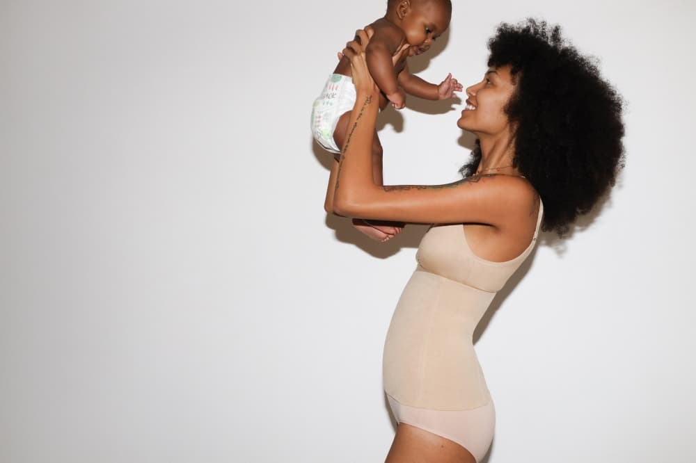 An image of a woman wearing the brand holding a baby. 