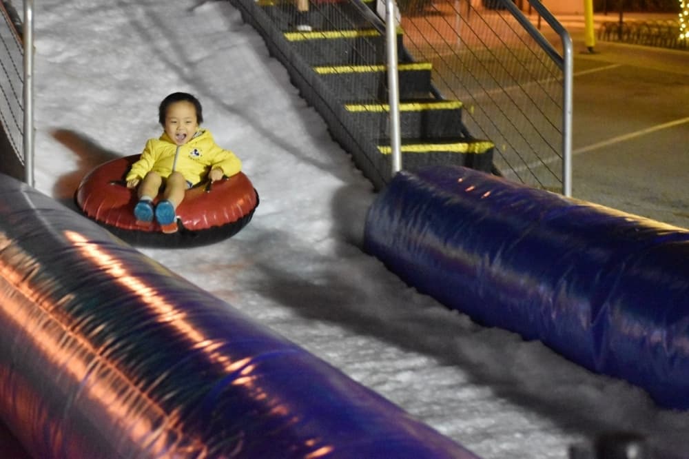 child going down a snow hill 