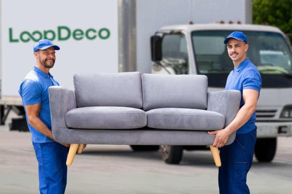 An image of two employees carrying a couch. 