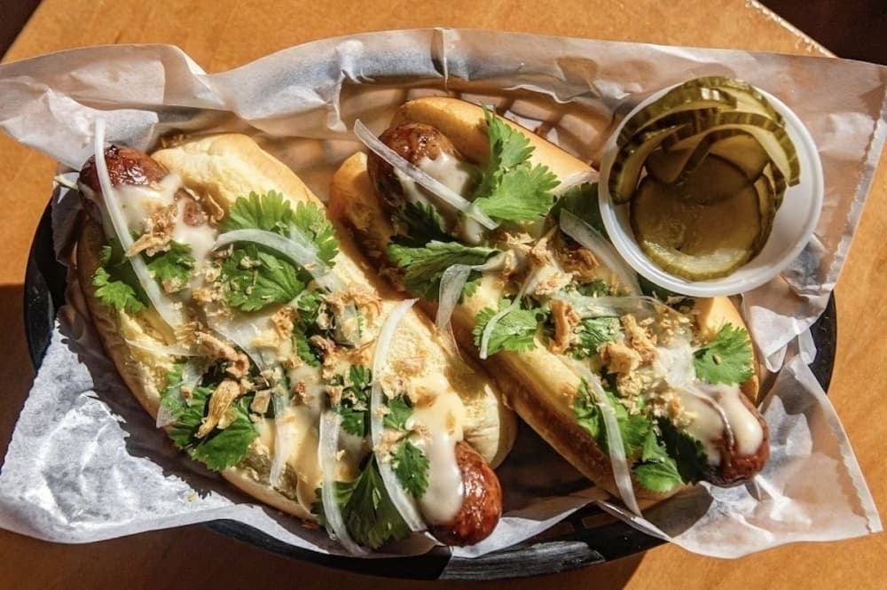 The Curry Queso Hotdog ($7.95) comes with smoked pork link, curry queso and is topped with onions, cilantro and shallots. (Courtesy Curry Boys BBQ)