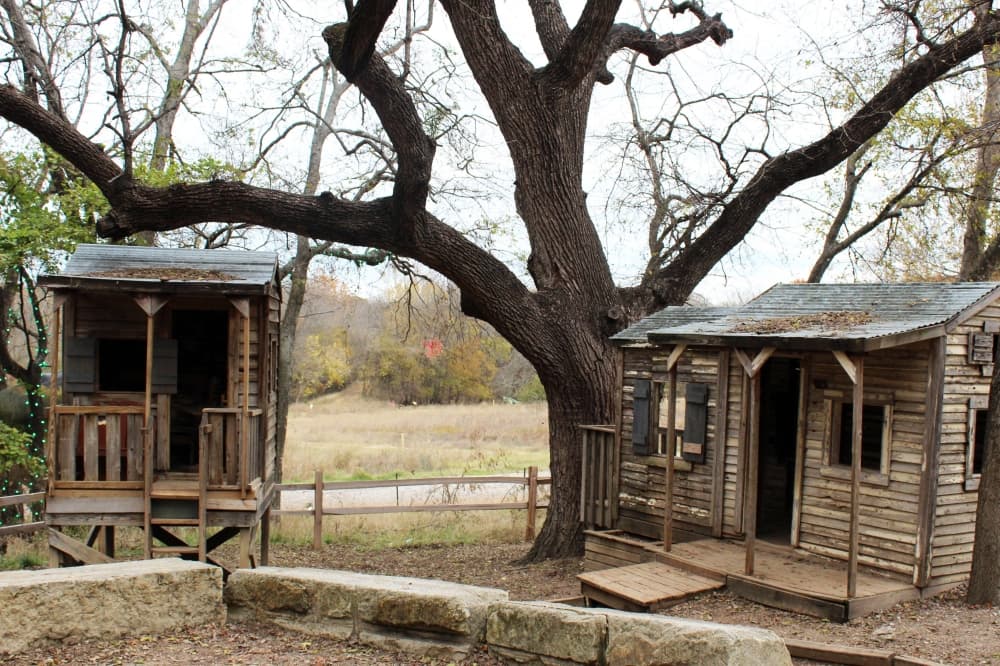 Wooden miniature houses next to a tree. 