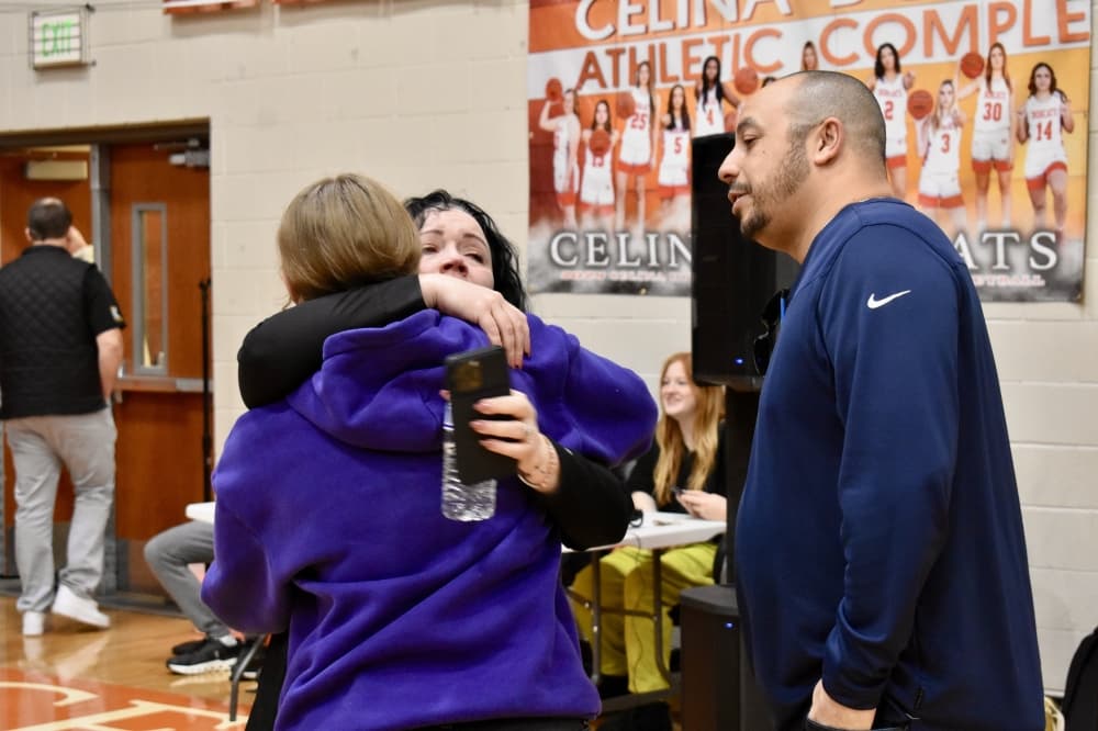 a mother hugs her daughter in a school gym after winning scholarships