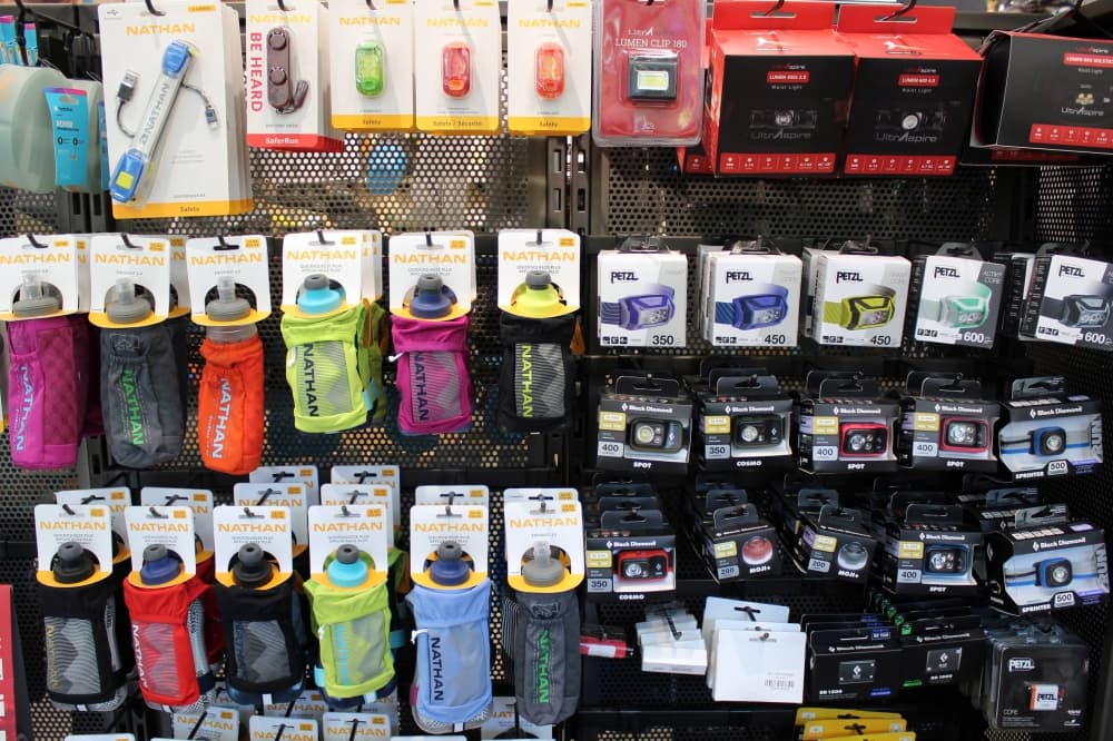 Water bottles and head lamps hanging on pegs in a store. 