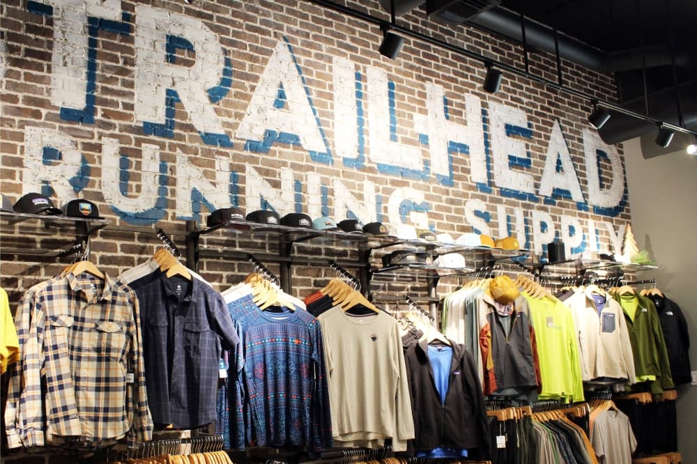 Clothing hanging on a wall with Trailhead Running Supply lettering painted on wall.