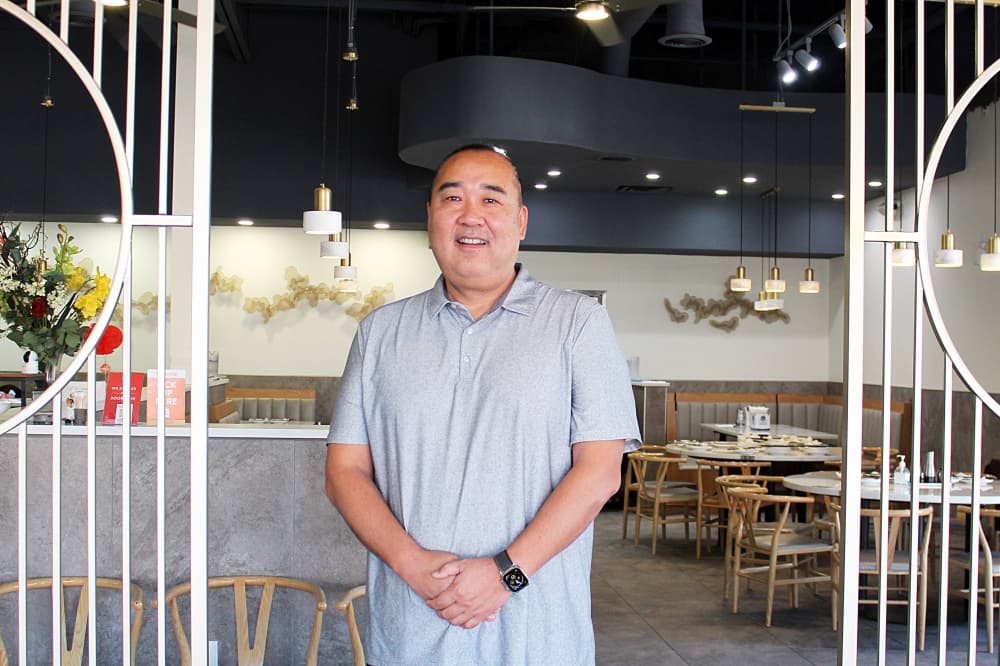 Male standing between two metal room dividers in a restaurant. 
