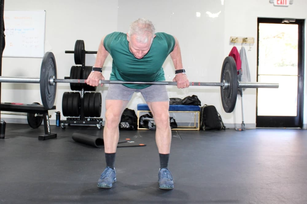 Male lifting a barbell with weights on either side. 