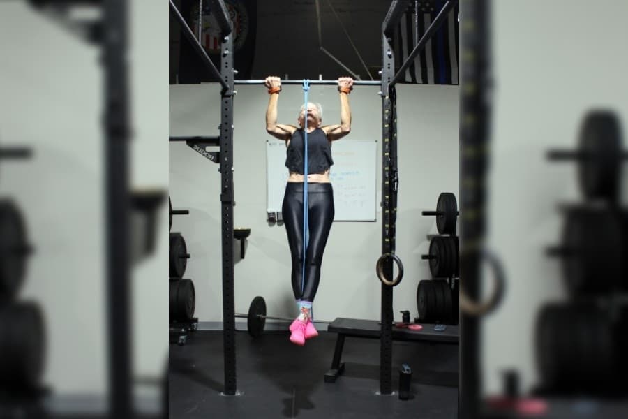 Female doing pull ups in a gym. 