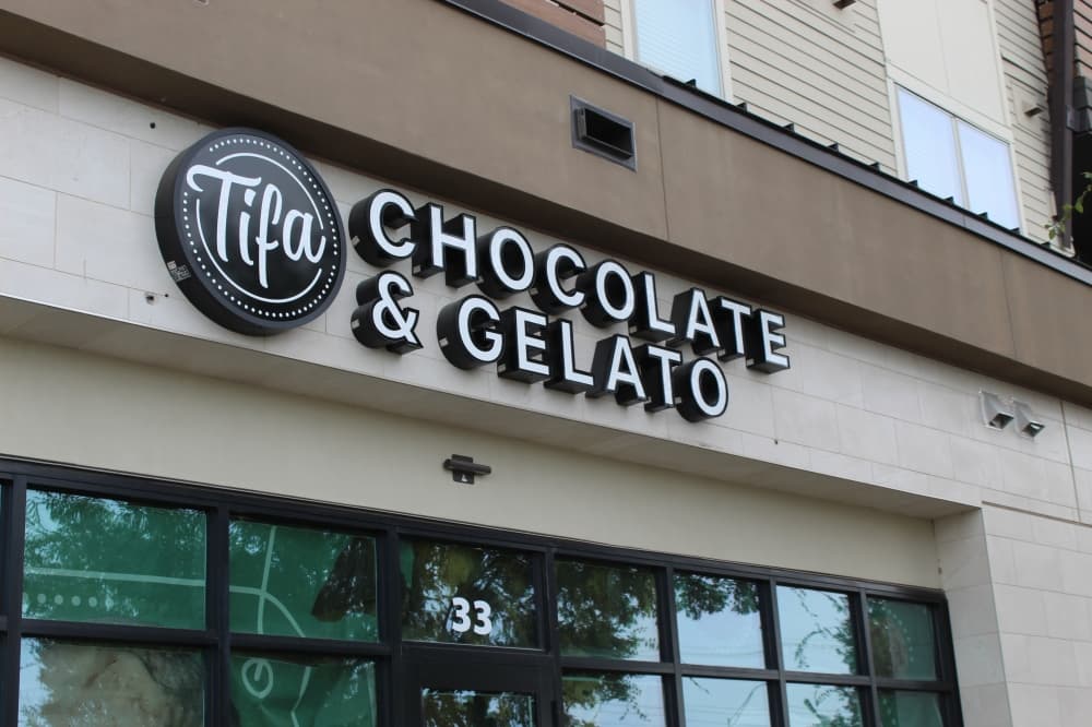 Image of Tifa Chocolate and Gelato storefront sign hanging over the entrance to the store. 