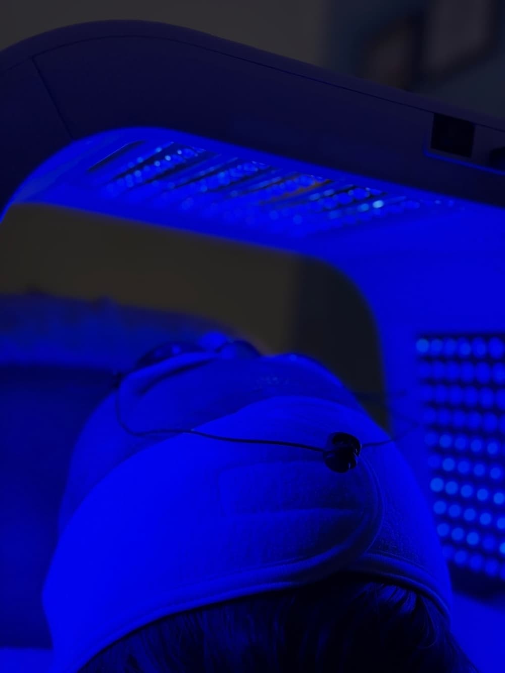 A person's face is positioned underneath a blue light.