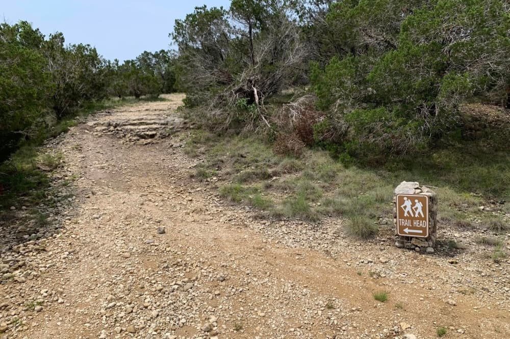 An image of a sign on the trail which says "trail head."