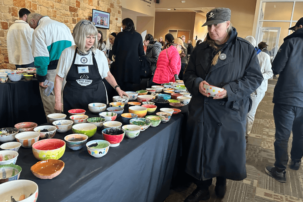 A table filled with hand-painted bowls is shown while people choose theirs.