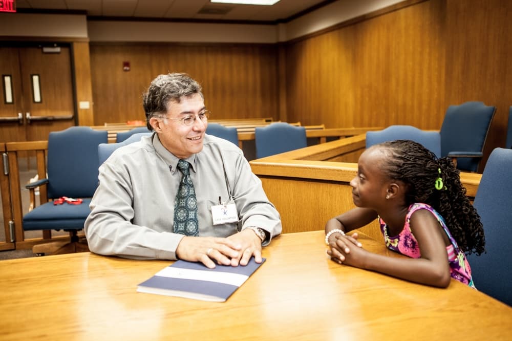 An image of a child sitting and speaking with someone in a court room. 
