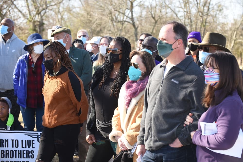 A group of adults and children listen to a speech at a previous event.