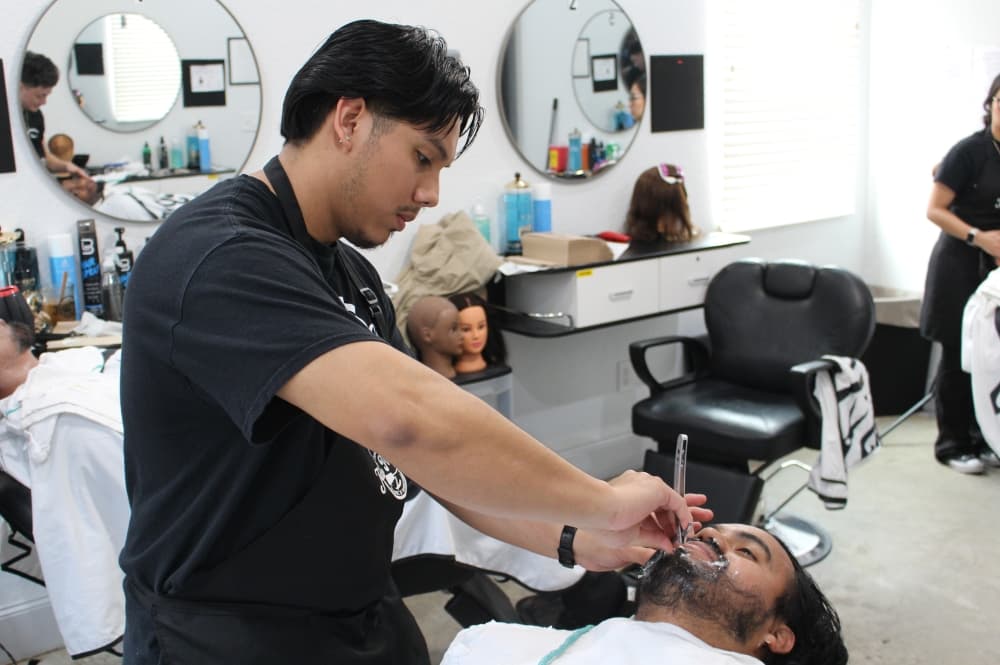 Daniel Cruz practices shaving with a straight razor on a fellow Jean Percy School of Barbering student during a Jan. 14 class.
