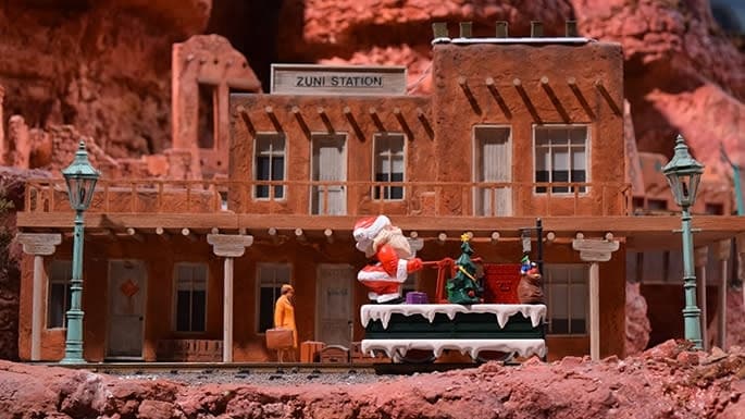 a Santa Claus figurine riding on a model train