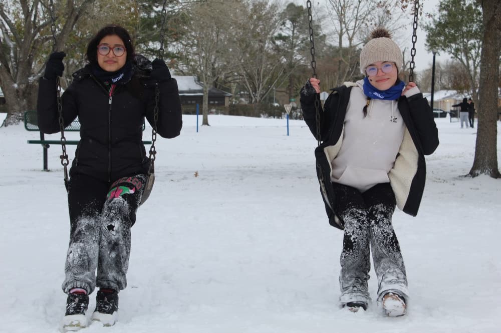 Two girls on a swing set in the snow