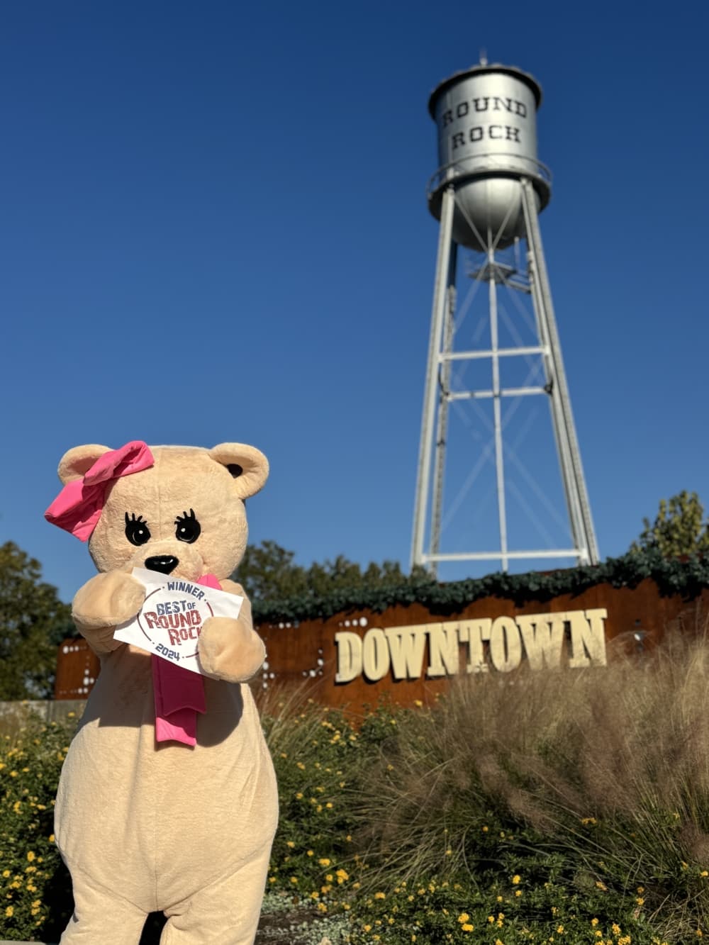 An image of the business' mascot with the downtown Round Rock sign. 