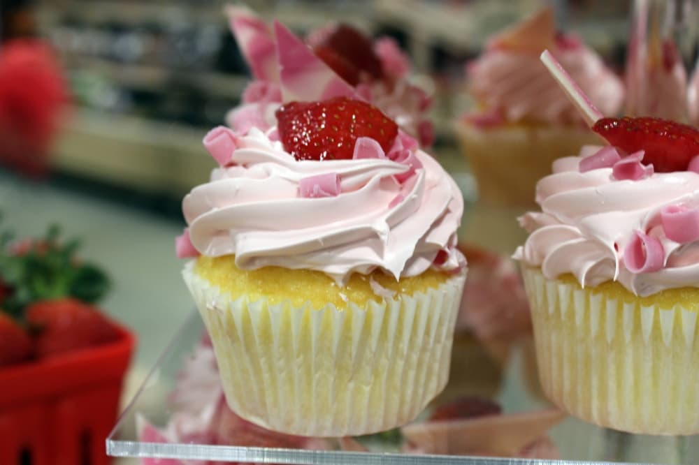 Yellow cupcakes with strawberry icing and strawberry garnish. 